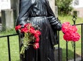 Closed up to a Black Virgin statue with red flowers in her hands