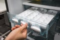 Closed up woman hand twisting for ice from the ice maker