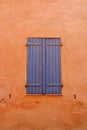 Closed vintage window of blue colour with old wooden shutters on the vibrant orange wall. Elegant retro architectural details Royalty Free Stock Photo