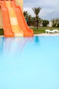 Closed water slides are in waterpark in a hotel, calm water surface of swimming pool, empty resort area