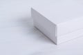 Closed white gift box with a lid on isolated wooden background. Crop image, side view, square box. Elegant eco-friendly