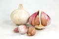 One closed white organic garlic bulb with skin and one opened semi-peeled garlic bulb and cloves isolated on white background Royalty Free Stock Photo