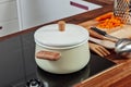 Closed white saucepan with wood pens on the black stove in the kitchen room. Cooking a soup, preparation Royalty Free Stock Photo