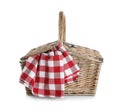 Closed wicker picnic basket with checkered blanket on white