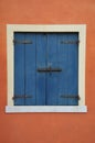 Window with blue shutter on orange wall Royalty Free Stock Photo