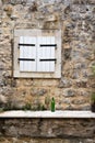 Closed window shutters in a stone wall with a green wine bottle Royalty Free Stock Photo