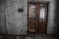 Closed wooden door in an abandoned building. Wooden chair. Broken glass in the door. Old abandoned interior. Royalty Free Stock Photo