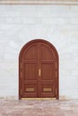 Closed wooden door with an arch in a stone white wall. Design and architecture Royalty Free Stock Photo