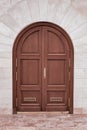 Closed wooden door with an arch in a stone white wall. Design and architecture Royalty Free Stock Photo