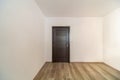 Closed wooden door in empty room, wooden flooring.  White walls Royalty Free Stock Photo
