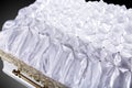 Closed wooden white coffin covered with white ritual blanket close-up.