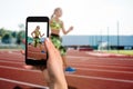Closely image of female hands holding mobile phone with photo camera mode on the screen. Cropped image of running woman.