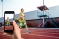 Closely image of female hands holding mobile phone with photo camera mode on the screen. Cropped image of running woman.