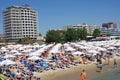 Closely positioned beach umbrellas and beach lounge chairs