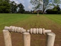 A closer up of cricket stumps and bails on a muddy strip