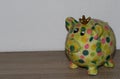 Closer view on a colorful piggy bank with a wooden underground and white background Royalty Free Stock Photo