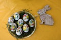 Closer view on easter eggs and a wooden easter bunny on a yellow tablecloth with copy space