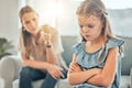 Closeup of an adorable little girl standing with arms crossed and looking upset while being scolded and reprimanded by