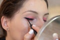 Closeup of an adult brunette aplying eye liner on herself, eyes closed while creating cat eyes Royalty Free Stock Photo