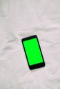 Closeup aerial view of white smart phone with green isolated screen on white wooden surface Royalty Free Stock Photo