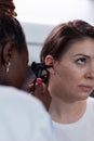 Closeup of african american otologist doctor analyzing woman patient ear