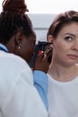 Closeup of african american otologist doctor checking woman patient ear