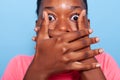 Closeup of african american young woman covering mouth having shocked facial expressions Royalty Free Stock Photo