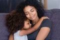 Closeup african daughter embracing mother sitting on couch at home