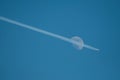 air plane condensation flying in front of the moon on blue sky background Royalty Free Stock Photo