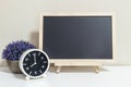 Closeup alarm clock for decorate show 8 o`clock with wood black board on white wood desk and cream wallpaper textured background