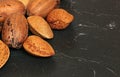 Closeup of almonds and pecan nuts in shell on dark board. Space for text on right side Royalty Free Stock Photo