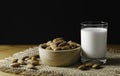 Closeup almonds in wooden bowl and glass milk on wooden background with copy space
