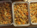 Closeup of 3 aluminum trays full of cooked biryani ready to go into the freezer for meal plan