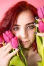 beauty face of the young red head woman with flowers. Attractive model with pink tulips. Royalty Free Stock Photo