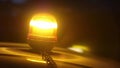 Closeup of an amber strobe warning light on the roof of a car at night