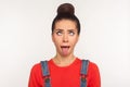 Closeup of amusing funny girl with hair bun looking up with eyes crossed and demonstrating tongue out