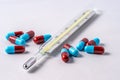 Closeup of an analog thermometer with pills spilled around it Royalty Free Stock Photo