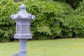 Closeup of an ancient style lamp post for oil lamps and lush green trees in the background. Buddhism and meditation concept