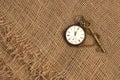 Closeup of ancient watch and key on old sackcloth. Time passing concept. Historical studies concept