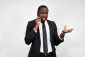 Closeup of angry young african man screaming while talking on smartphone over grey background Royalty Free Stock Photo