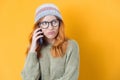 Closeup annoyed girl on the phone, isolated on yellow background. Annoying female talking. Nuisance and smart phone