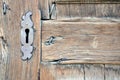 Closeup of antique wooden door with metallic keyhole and nails