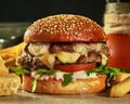 Burger with two patties, cheese, tomatoes and greens in sesame bun