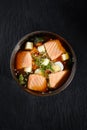 Closeup on appetizing ishikari miso soup with salmon in a black bowl, on black background, japanese food. Royalty Free Stock Photo