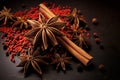 A closeup of aromatic star anise cinnamon sticks and vibrant red peppercorns top view on a dark textured surface