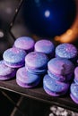 Closeup of an array of purple space themed macarons on a black tray