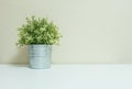 Closeup artificial plant in pot for decorate on blurred wooden white desk and wall textured background in room with copy space