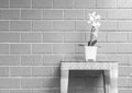 Closeup artificial plant with white orchid flower on flower pot on wood weave table on blurred brick wall texture background , bea