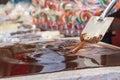 Artisan chocolate worker mixing melting chocolate with spatulas on a table