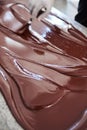 Worker spreading melted artisanal chocolate out on a factory table